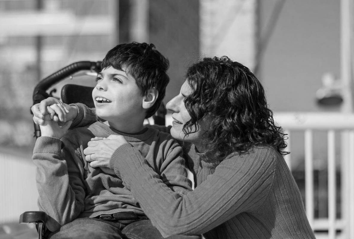 Mother embracing son with cerebral palsy